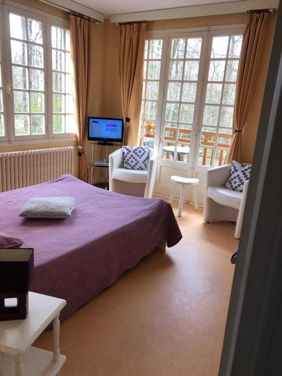 a bedroom with a bed and chairs and windows at Appartement bagnoles in Bagnoles de l'Orne