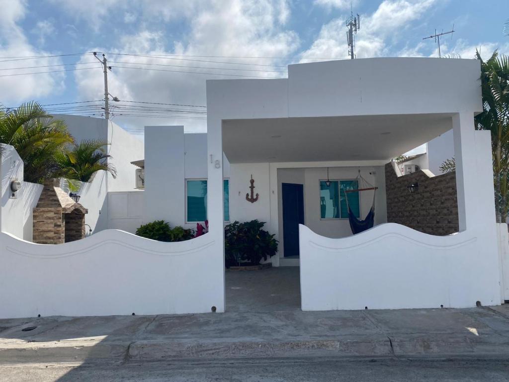 Uma casa branca com um portão à frente. em Salinas villa em La Libertad