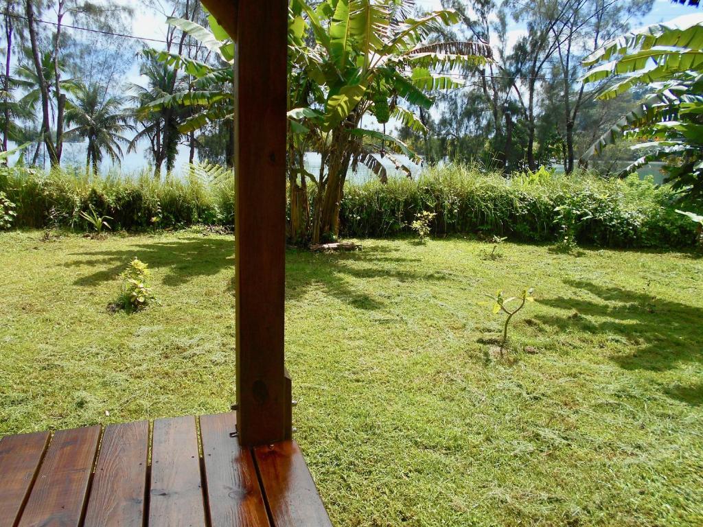 a wooden porch with a field of grass and trees at Fare Hanuatai in Tevaitoa