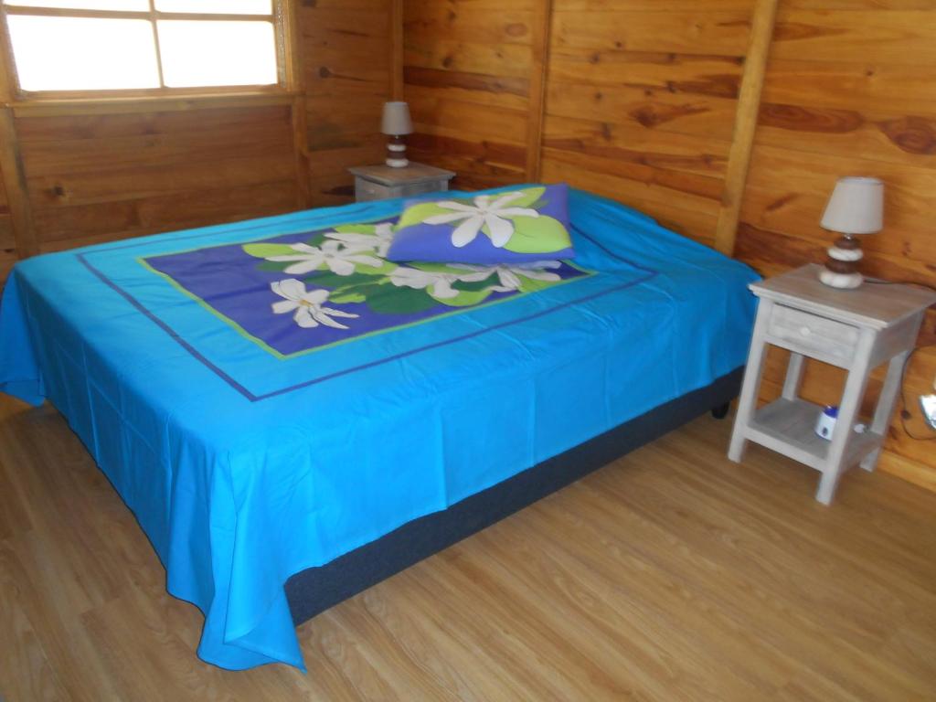 a blue bed in a wooden room with a table at Fare Hanuatai in Tevaitoa