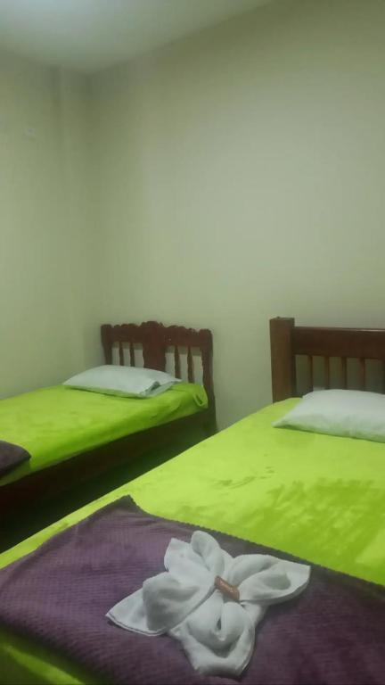 two beds with green sheets with a white flower on them at Mi Balconcito in Salento