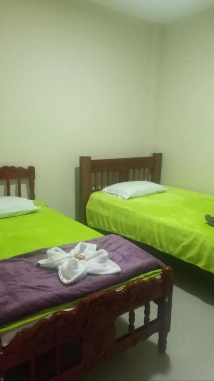 two beds with green sheets and white towels on them at Mi Balconcito in Salento