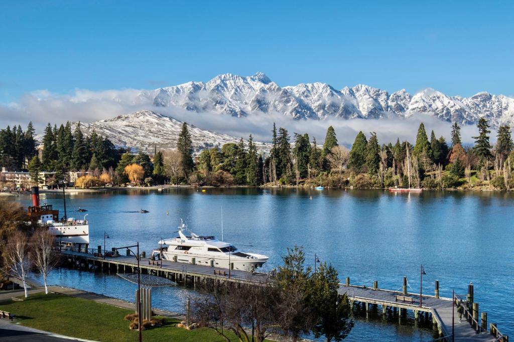 a boat docked at a dock on a lake with mountains at The Waterfront in Queenstown