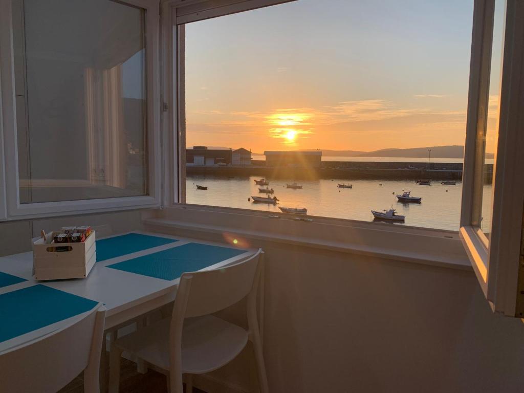 Zimmer mit einem Tisch und einem Fenster mit Booten im Wasser in der Unterkunft O CUBERTO DE ROBERTA in O Pindo