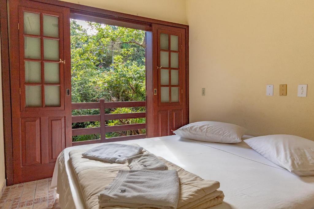 a bedroom with two beds and a window with a door at Pousada do Marquinhos in Trindade