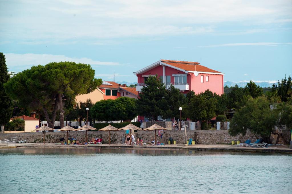un gruppo di tavoli e ombrelloni su una spiaggia vicino all'acqua di Apartments Danijela 2 a Sukošan (San Cassiano)