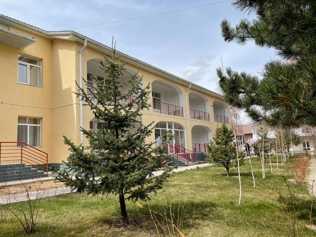 een geel gebouw met een boom ervoor bij Apartment in Raduga West, Issyk-Kul in Tamchy