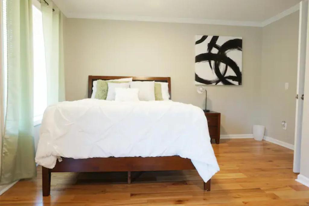 a bedroom with a bed with white sheets and a wooden floor at Atlanta Unit 1 Room 1 - Peaceful Private Master Bedroom Suite with Private Balcony in Atlanta