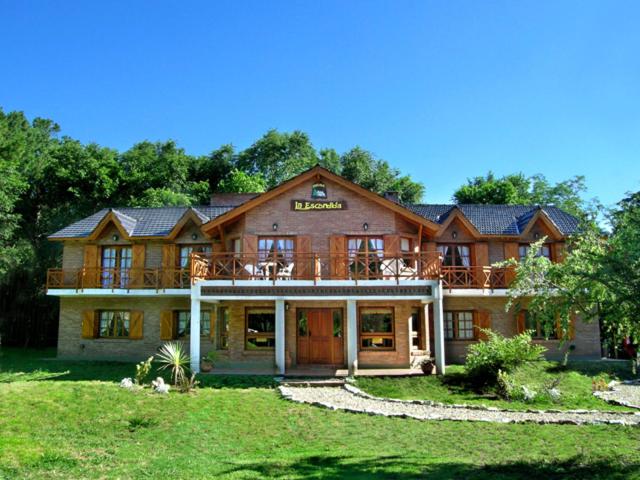 een groot houten huis met een grote veranda bij Posada La Escondida in Villa General Belgrano
