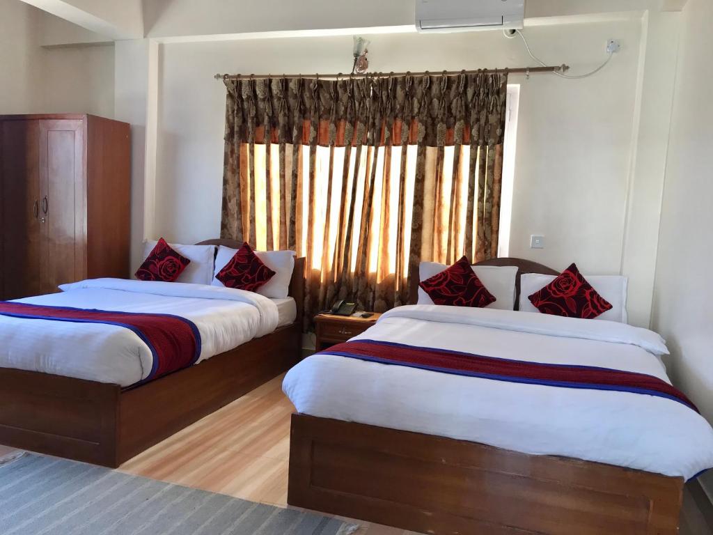a hotel room with two beds and a window at Hotel Asia in Pokhara