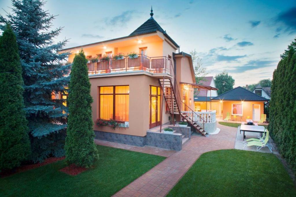 a large house with a staircase in a yard at Sunshine SH apartmanház in Zamárdi