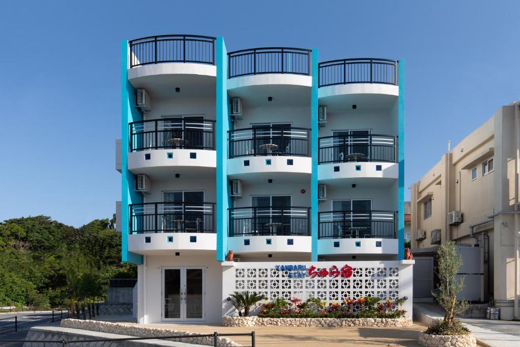 un edificio de apartamentos azul y blanco con balcones en YANBARU STAY ちゅら宿, en Nago