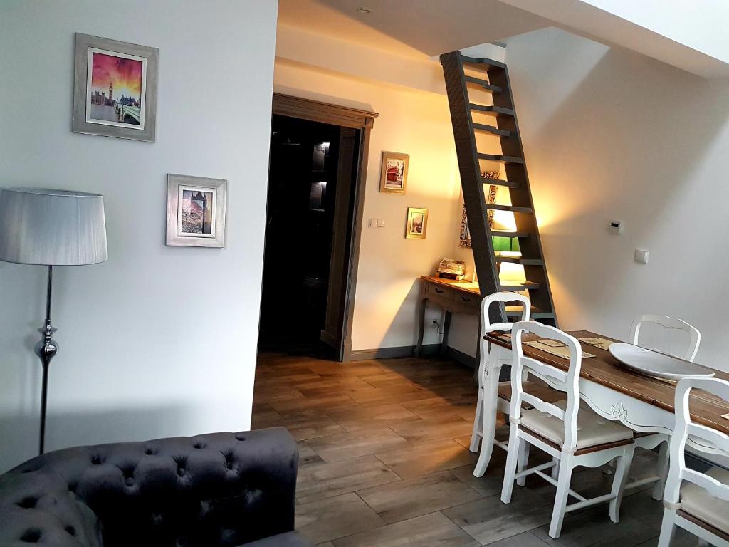 een woonkamer met een tafel en stoelen en een trap bij Apartament Old England in Żywiec