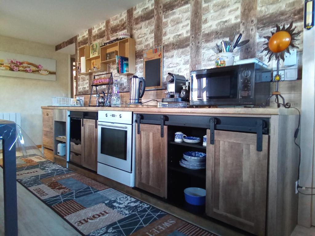 eine Küche mit einer Theke mit einem Herd und einer Mikrowelle in der Unterkunft Logement de charme in Coinches