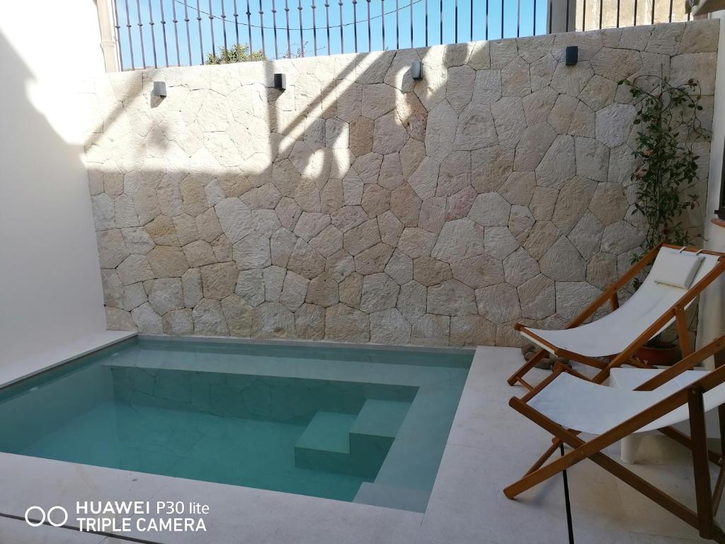 una silla y una piscina junto a una pared de piedra en Ermitans, en Petra