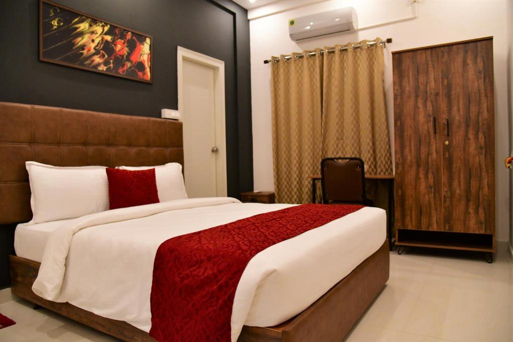 a bedroom with a large bed with a red blanket at Xcel Luxury Hotel Apartments-Home Living Redefined in Mysore