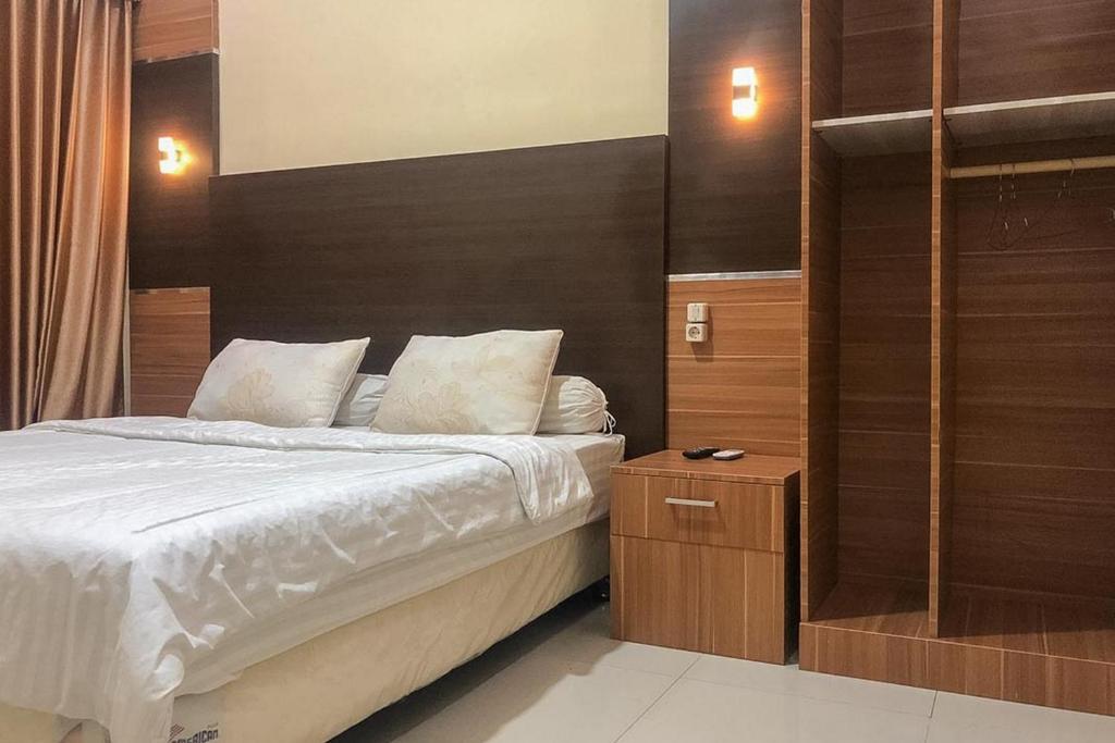 1 dormitorio con 1 cama con sábanas blancas y paredes de madera en RedDoorz Syariah near Alun Alun Bima en Bima