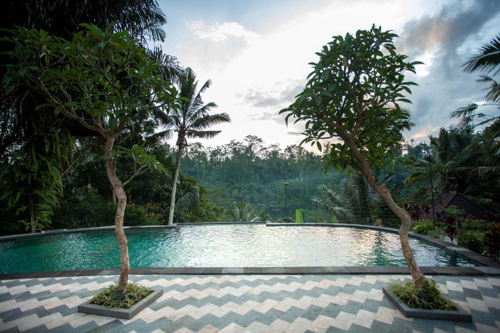a swimming pool with two trees in the middle at Campuhan Sebatu Resort in Tegalalang