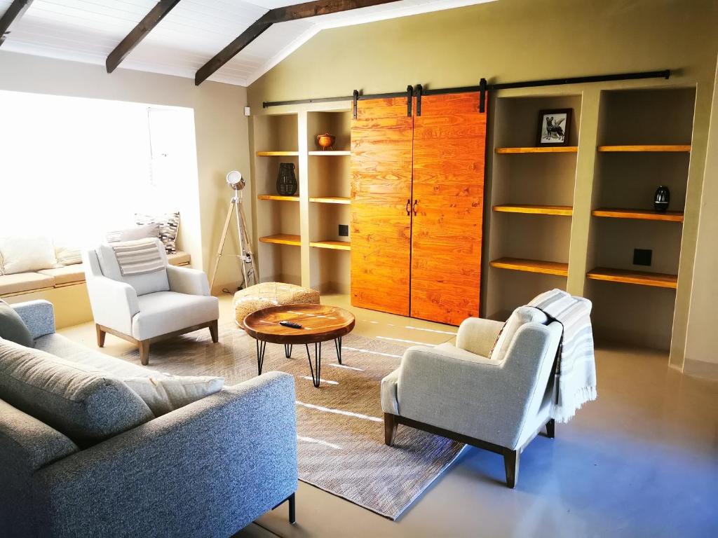 een woonkamer met een bank, twee stoelen en een tafel bij Ostrich Hide in Marloth Park