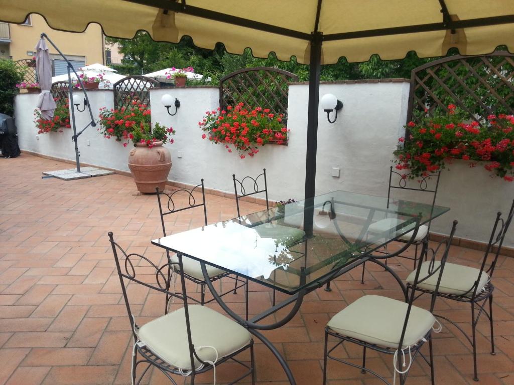 アッバディーア・サン・サルヴァトーレにあるLa terrazza di Elenaの花の咲く中庭にガラスのテーブルと椅子