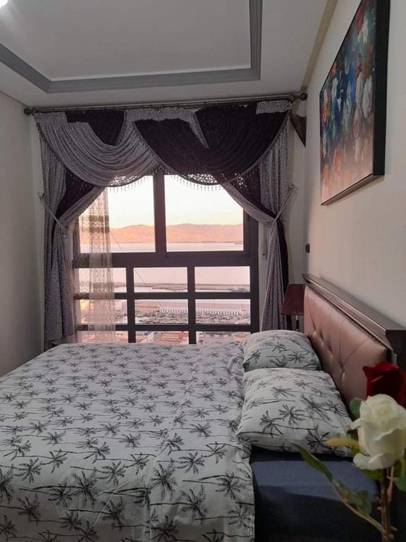 a bedroom with a bed and a large window at Al-marsa2 in Al Hoceïma