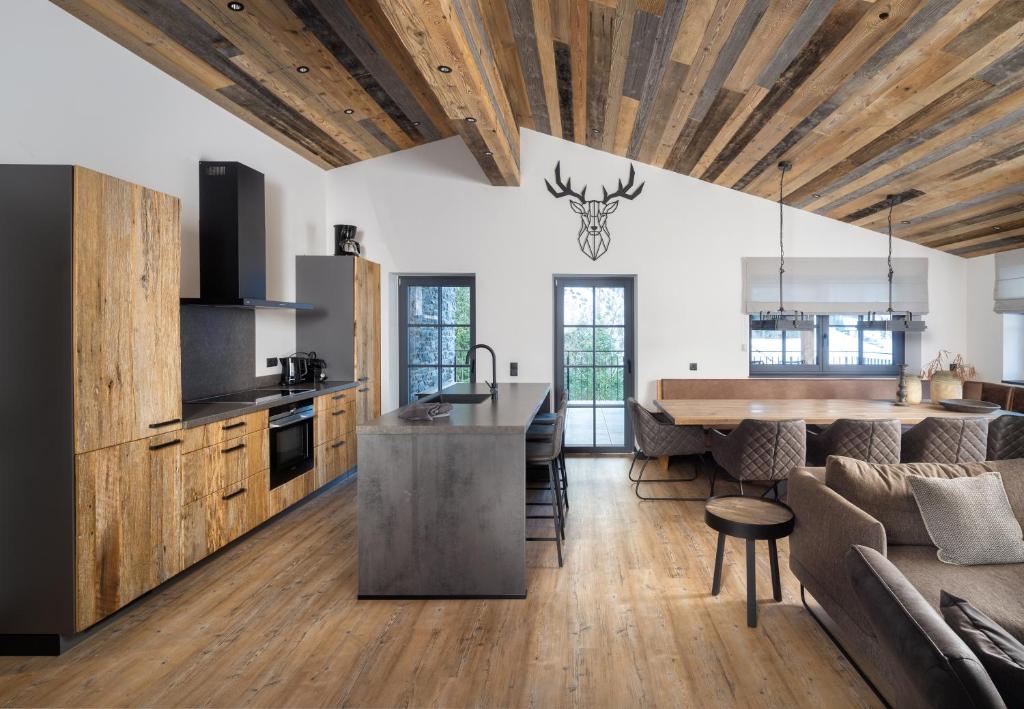 an open kitchen and living room with wooden ceilings at Nova Gosta Montafon NEU in Gaschurn