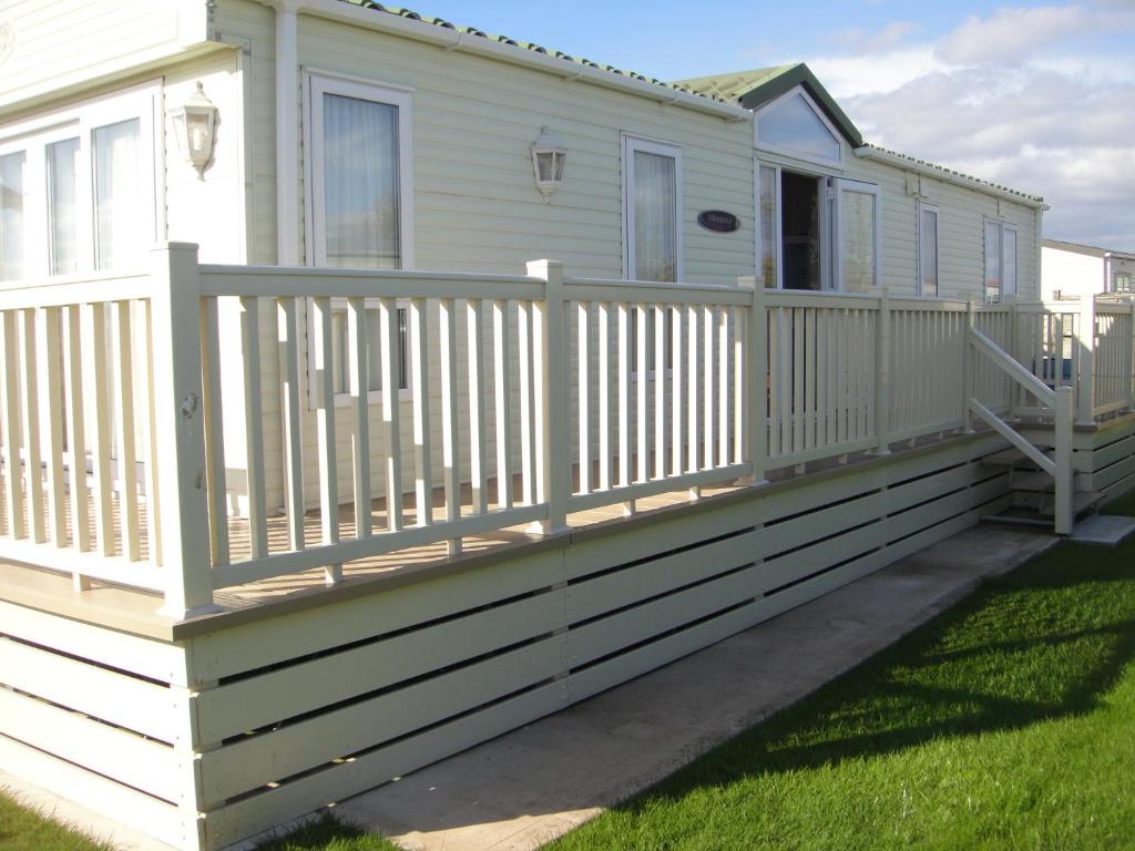 ein Haus mit einem weißen Zaun und einer Veranda in der Unterkunft Bri-ann's Seaside Holiday Home NO VANS OR LARGE VEHICLES in Selsey