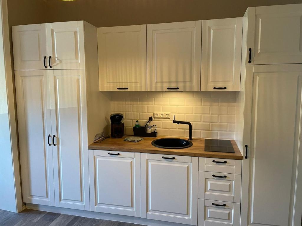 a kitchen with white cabinets and a sink at Strandallee Ferienwohnung in Timmendorfer Strand