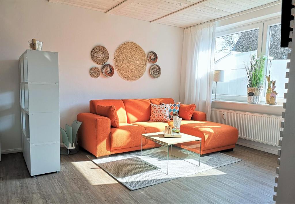 an orange couch in a living room with a table at Butze Ferienapartment in Büsum