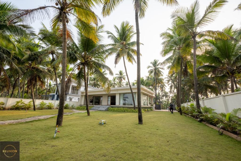 a man walking a dog in front of a house with palm trees at Reunion Ocean Elite - Beach House in Udupi