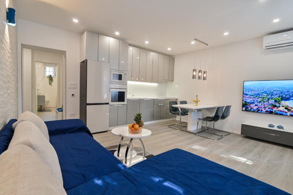a living room with a blue couch and a kitchen at Bacvice 21 in Split