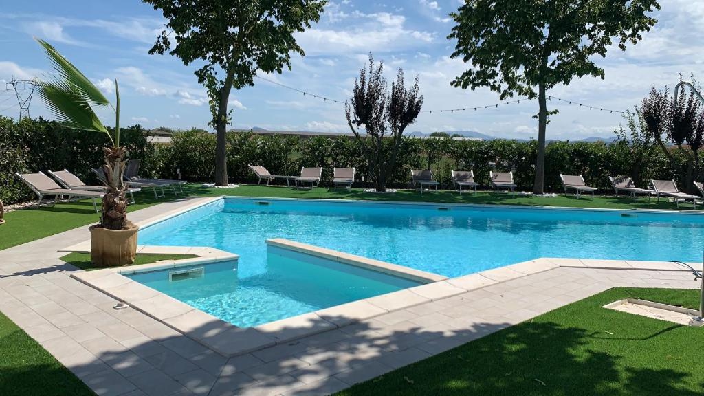 a swimming pool in a yard with chairs and trees at Il Giullare by agriturismo Borgo Castellaccia in Cesenatico