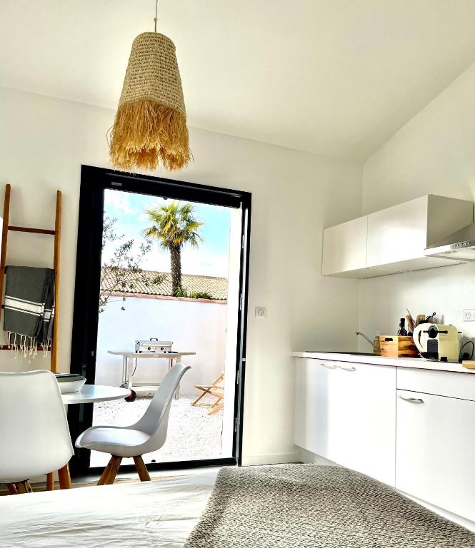 une cuisine avec une table et une chaise ainsi qu'une fenêtre dans l'établissement Maisonnette à proximité plage et port de St-Martin, à Saint-Martin-de-Ré