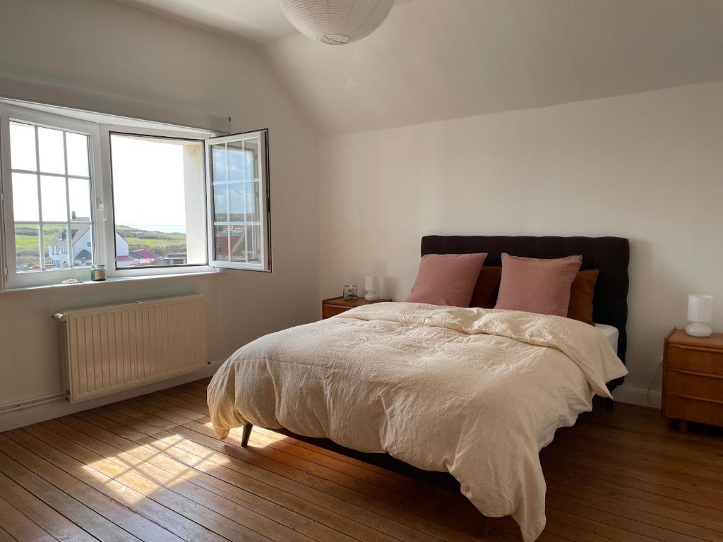 a white bedroom with a large bed with pink pillows at La Villa L'Escale in Audresselles