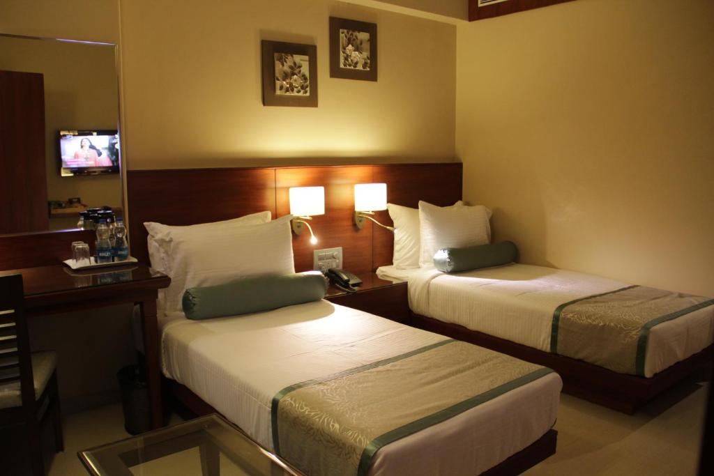 una camera d'albergo con due letti e uno specchio di Hotel Green Olive ad Aurangabad