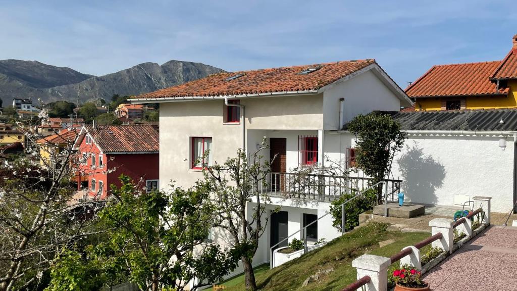 ein weißes Haus auf einem Hügel mit Bergen im Hintergrund in der Unterkunft Apartamentos - Casa El Ancla in Celorio