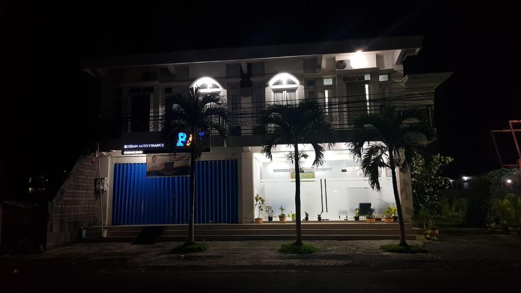 a building with a blue gate and palm trees at night at Rezka Roomz Syari'ah in Ende