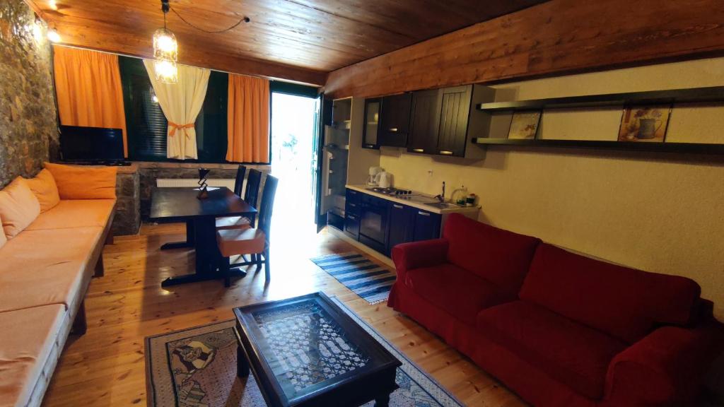 ein Wohnzimmer mit einem roten Sofa und einem Tisch in der Unterkunft Traditional cozy apartments in Livadi Parnassos in Kalívia