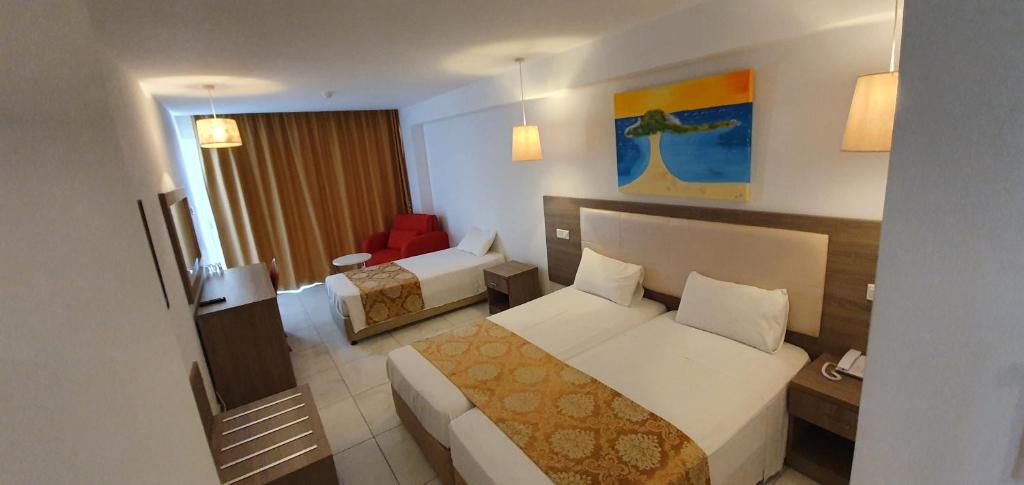 a hotel room with two beds and a chair at Corfu Hotel in Ayia Napa
