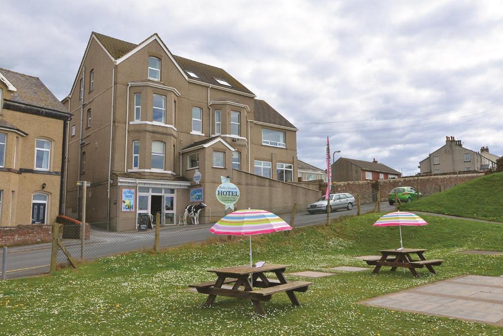 two picnic tables with umbrellas in front of a building at Bailey Ground Hotel in Seascale