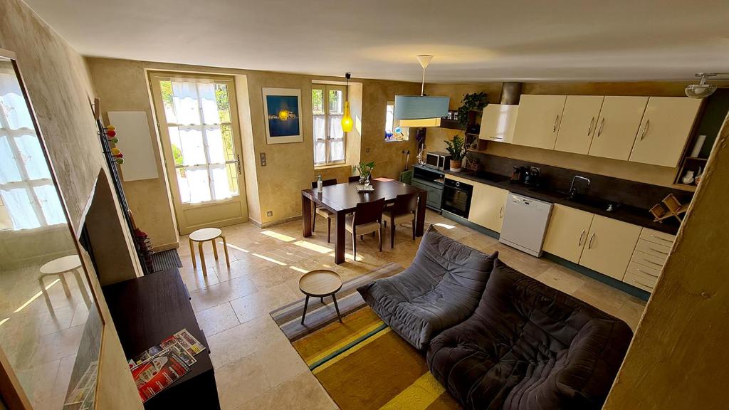 une cuisine et un salon avec un canapé et une table dans l'établissement Le jardinet de Rosa Maison de village, à Eygalières