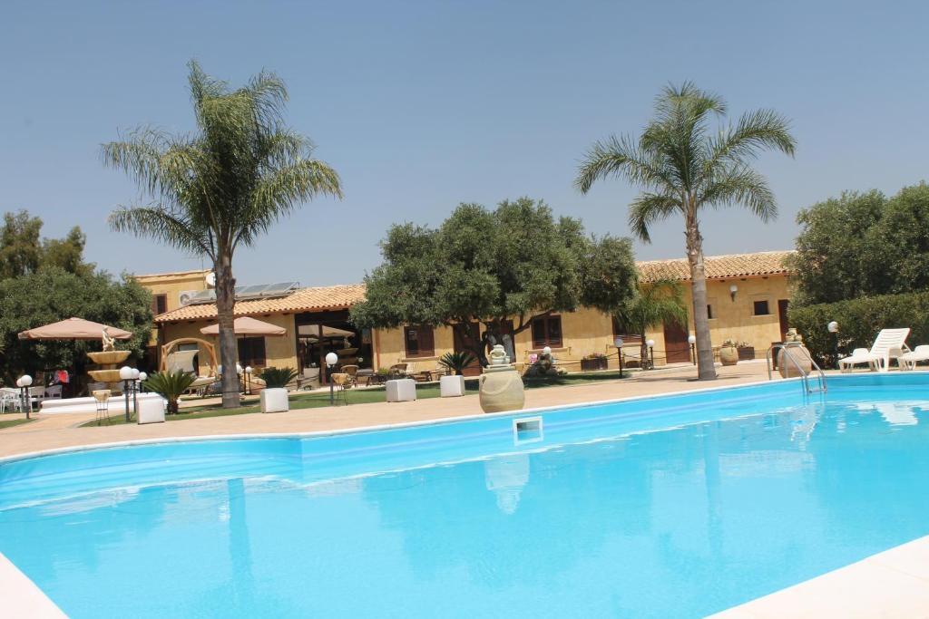uma grande piscina num resort com palmeiras em Villa Alisia em Zingarello