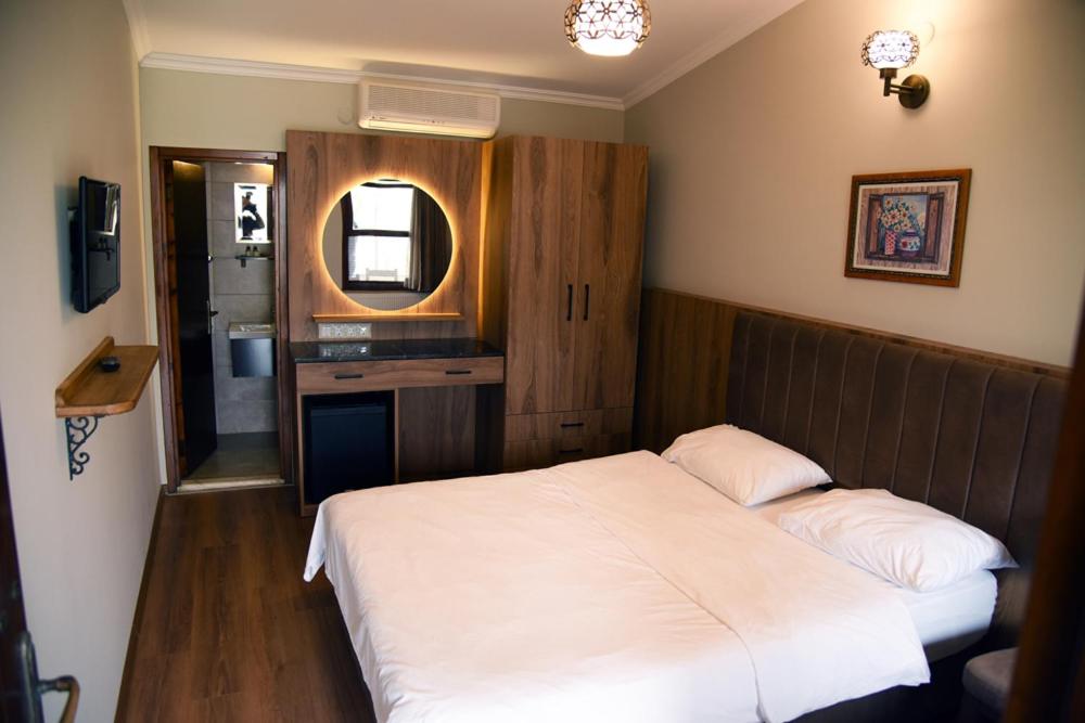 a bedroom with a white bed and a mirror at Fener Motel in Şile