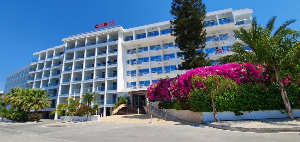 a large white building with pink flowers in front of it at Corfu Hotel in Ayia Napa