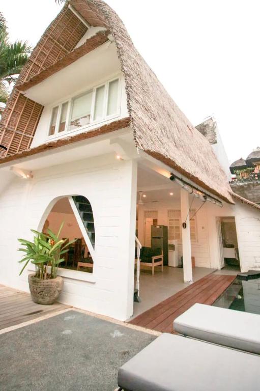 a white house with a thatched roof and a patio at Villa Olivia in Seminyak