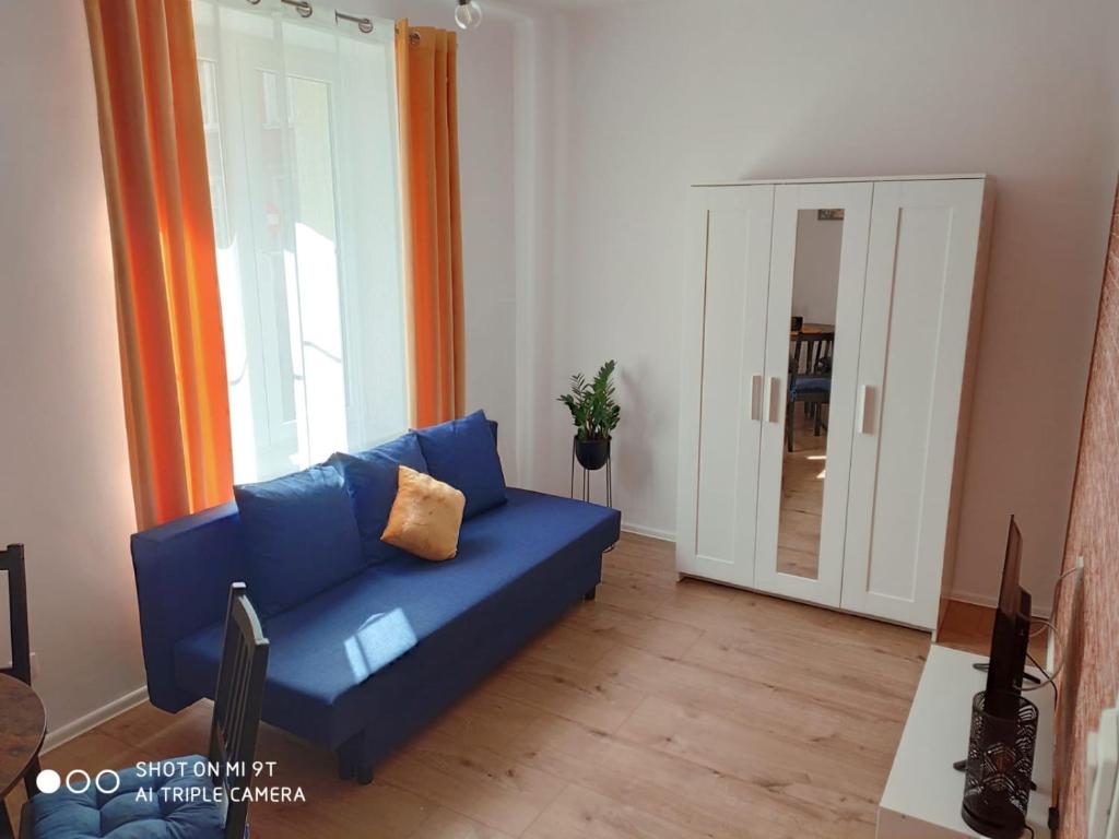 a blue couch in a living room with a mirror at Apartament Anastazja in Koszalin