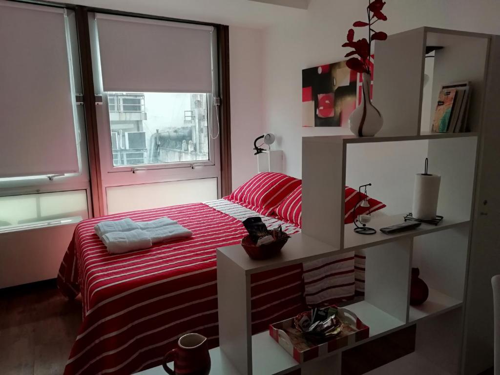 1 dormitorio con cama roja y ventana en Silvia´s Studio en Buenos Aires