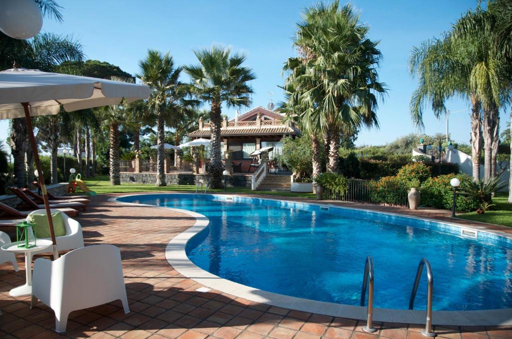 una piscina con palmeras y una casa en Villa Papardo, en Giarre