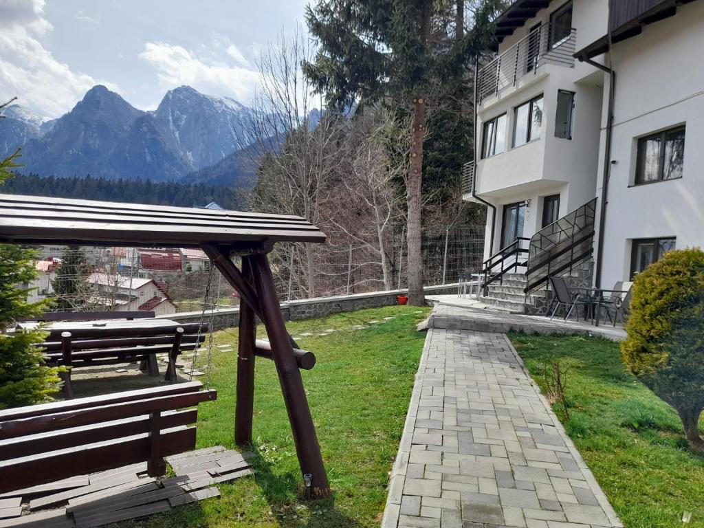 a bench and a building with mountains in the background at Casa Morarului in Buşteni