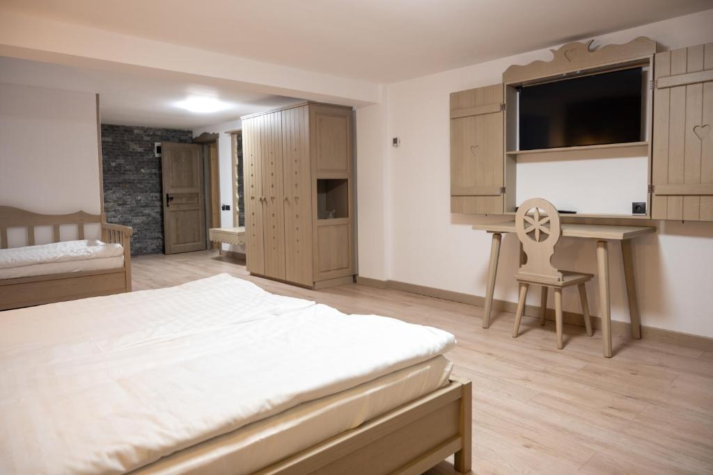 a bedroom with a bed and a desk and a chair at Pension Mama Cozonacilor in Bran